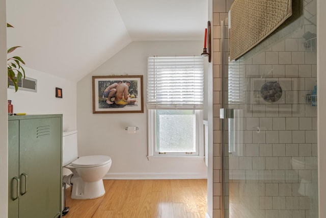 full bathroom with vaulted ceiling, wood finished floors, a tile shower, and toilet