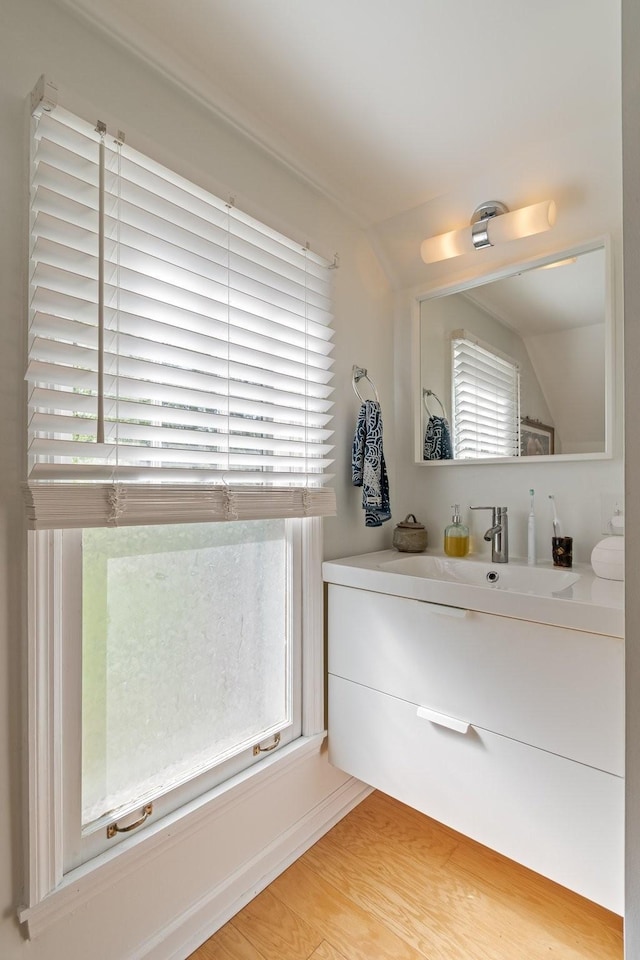 bathroom with vanity, wood finished floors, and vaulted ceiling