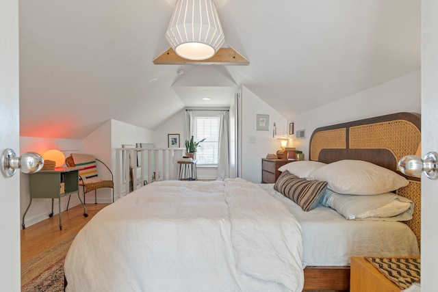 bedroom featuring wood finished floors, lofted ceiling, and baseboards