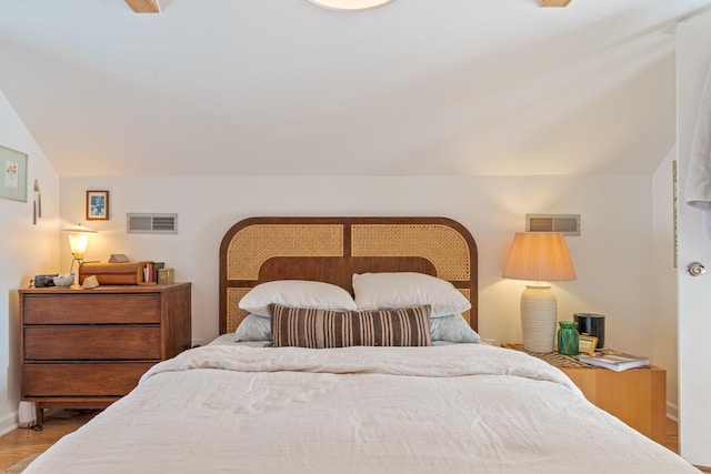 bedroom with wood finished floors, lofted ceiling, and baseboards