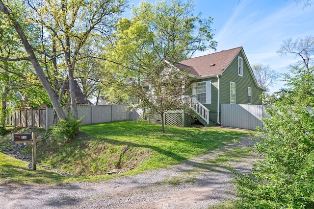 view of side of property with dirt driveway, fence, and roof with shingles
