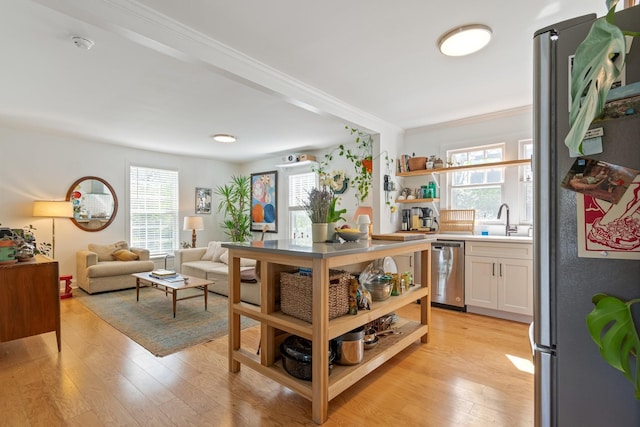 kitchen with stainless steel appliances, open shelves, ornamental molding, healthy amount of natural light, and light wood-type flooring