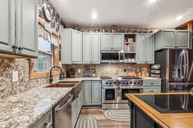 3560 Tyree Springs Rd, Hendersonville, TN 37075 - kitchen featuring appliances with stainless steel finishes, a sink, open shelves, wood finished floors, and light stone counters