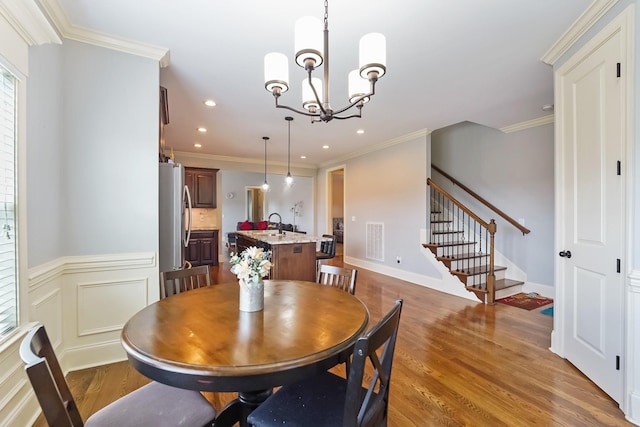 dining room with wood finished floors, stairway, a chandelier, crown molding, and recessed lighting