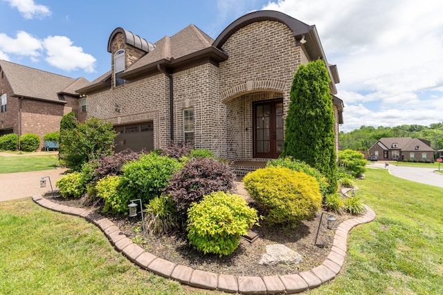 view of front facade with french doors, brick siding, a front lawn, and a garage