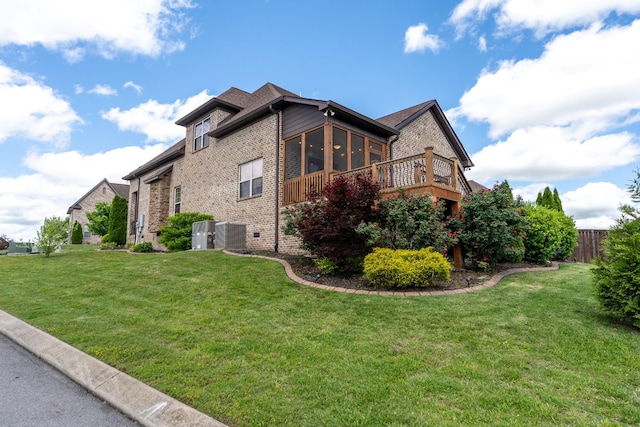 view of home's exterior featuring a sunroom, brick siding, and central air condition unit