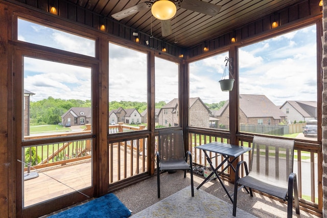 sunroom / solarium with a ceiling fan, a residential view, and plenty of natural light