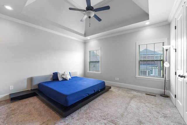 carpeted bedroom with a raised ceiling, recessed lighting, multiple windows, crown molding, and baseboards