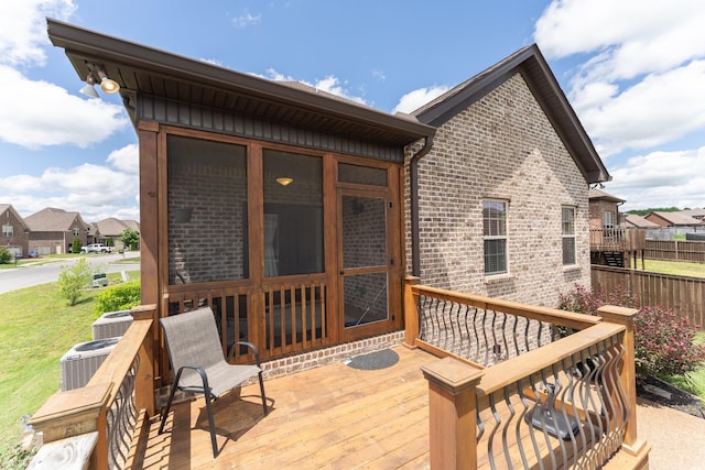 wooden deck featuring a sunroom, a residential view, and cooling unit