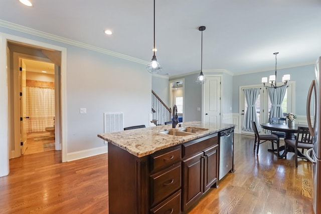 kitchen with a sink, dishwasher, dark brown cabinetry, hanging light fixtures, and wood finished floors