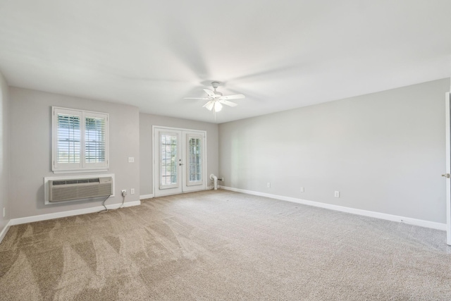 carpeted spare room featuring a ceiling fan, baseboards, a wall mounted AC, and french doors