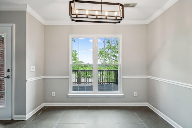 unfurnished dining area with crown molding, dark tile patterned flooring, baseboards, and a chandelier