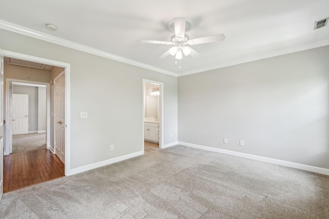 unfurnished bedroom with attic access, carpet, baseboards, crown molding, and ceiling fan
