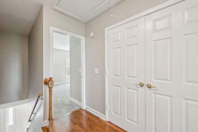 hallway with an upstairs landing, wood finished floors, and baseboards