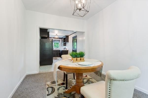 dining area with a chandelier, carpet, and baseboards