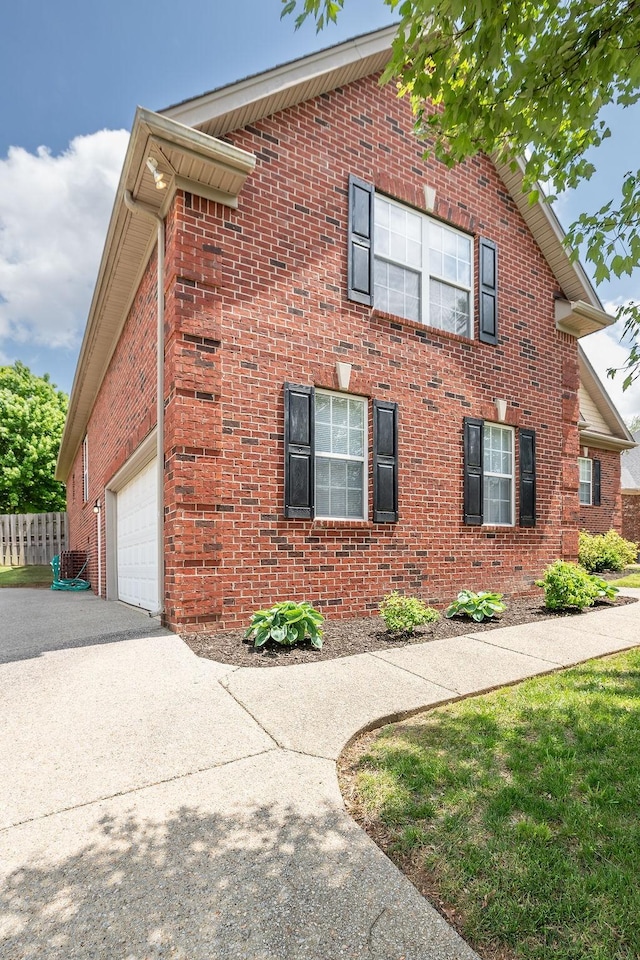 2184 Loudenslager Dr, Thompsons Station, TN 37179 - view of home's exterior featuring concrete driveway, brick siding, a garage, and fence