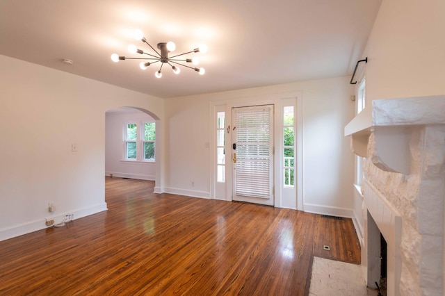 2219 Blair Blvd, Nashville, TN 37212 - unfurnished living room with a tiled fireplace, arched walkways, wood finished floors, a chandelier, and baseboards