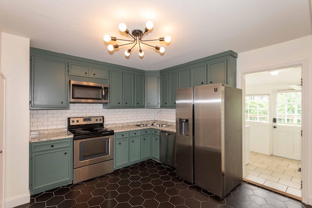 2219 Blair Blvd, Nashville, TN 37212 - kitchen featuring appliances with stainless steel finishes, a chandelier, tasteful backsplash, dark tile patterned floors, and light stone counters