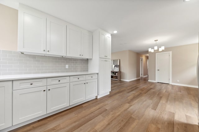 1614 Shady Cir, Lebanon, TN 37087 - kitchen featuring light countertops, light wood-style flooring, tasteful backsplash, white cabinets, and a chandelier