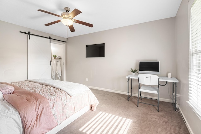 carpeted bedroom with a barn door, baseboards, and a ceiling fan