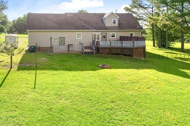 back of property with a deck and an outdoor fire pit