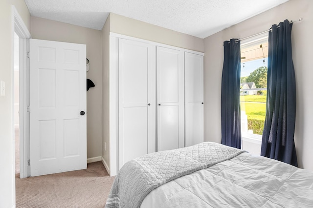 carpeted bedroom featuring a closet, a textured ceiling, and baseboards