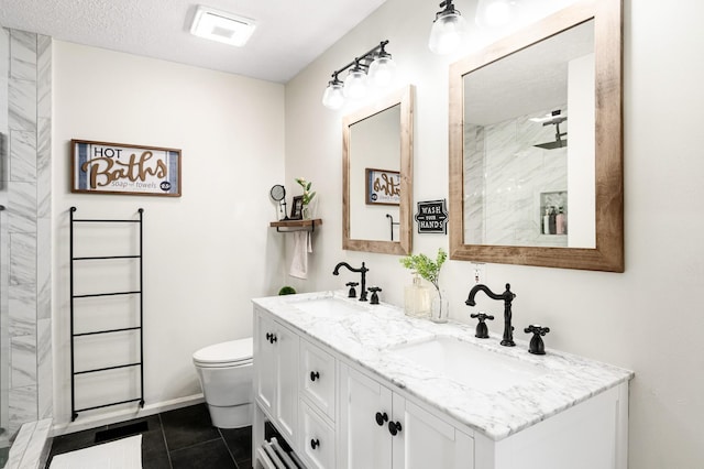 bathroom with tiled shower, tile patterned flooring, toilet, double vanity, and a textured ceiling