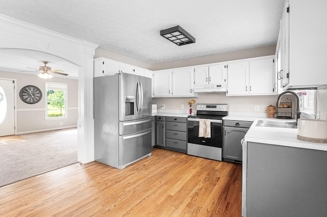 kitchen featuring appliances with stainless steel finishes, under cabinet range hood, gray cabinets, a sink, and light countertops