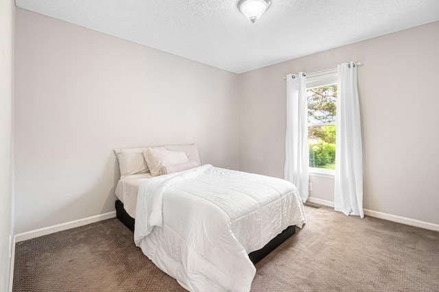 bedroom with a textured ceiling, carpet floors, and baseboards