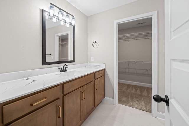 bathroom with vanity, a walk in closet, and tile patterned flooring