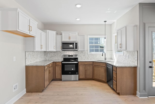 kitchen with appliances with stainless steel finishes, a sink, light stone countertops, brown cabinets, and white cabinetry