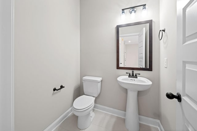 bathroom featuring toilet, baseboards, tile patterned flooring, and a sink
