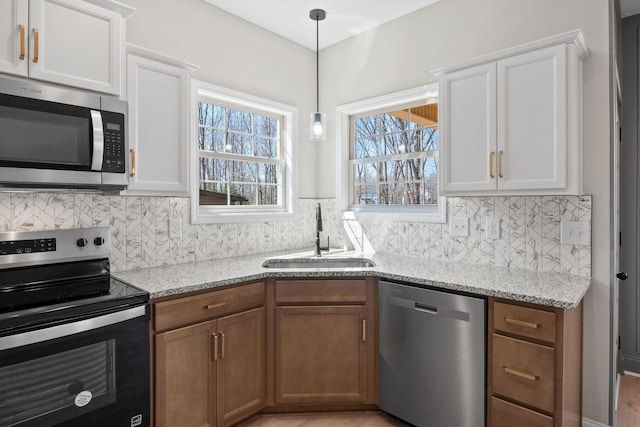 kitchen featuring appliances with stainless steel finishes, a sink, healthy amount of natural light, and light stone countertops