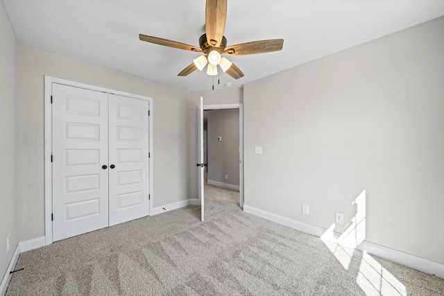 unfurnished bedroom featuring carpet floors, a closet, baseboards, and ceiling fan