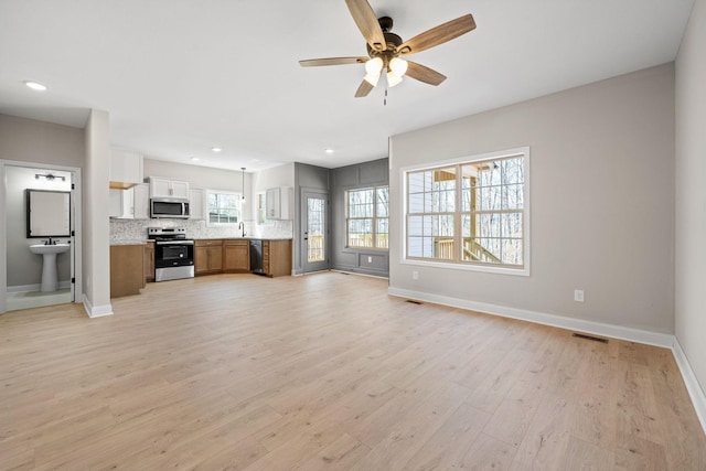unfurnished living room featuring baseboards, light wood finished floors, a ceiling fan, and recessed lighting