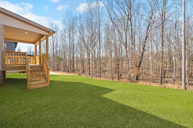view of grassy yard featuring a deck and stairs