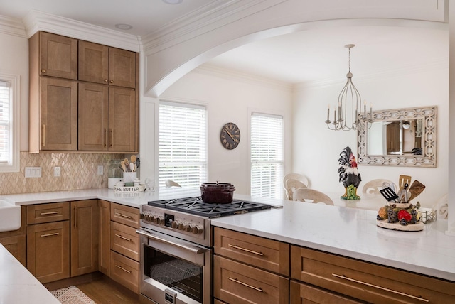 635 Band Dr, Franklin, TN 37064 - kitchen with high end stainless steel range, arched walkways, a peninsula, crown molding, and hanging light fixtures