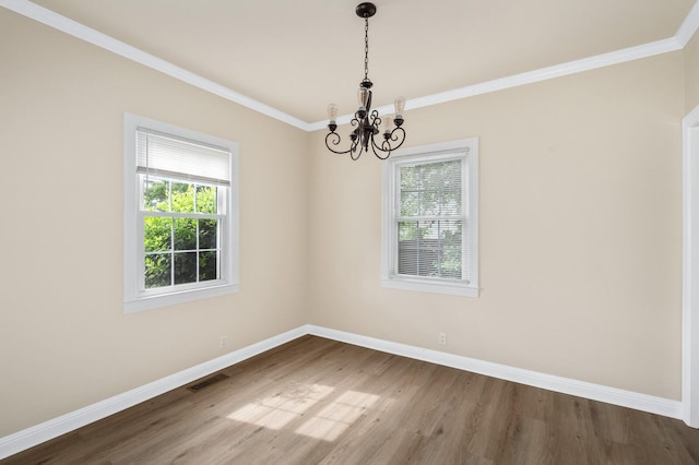 spare room with a chandelier, baseboards, wood finished floors, and crown molding