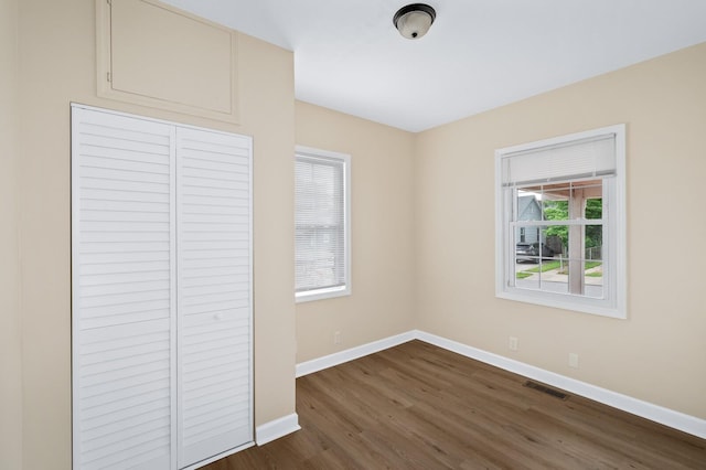 unfurnished bedroom with baseboards, dark wood-style floors, and a closet