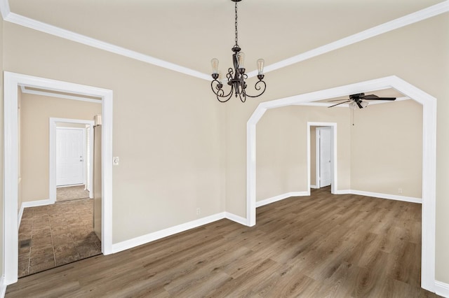 unfurnished dining area featuring wood finished floors, a chandelier, baseboards, crown molding, and a ceiling fan