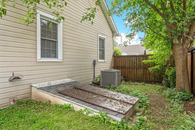 view of side of home with cooling unit and fence