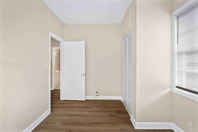 unfurnished bedroom with wood finished floors, baseboards, and a closet