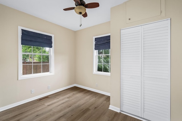 unfurnished bedroom with baseboards, wood finished floors, a closet, and a ceiling fan