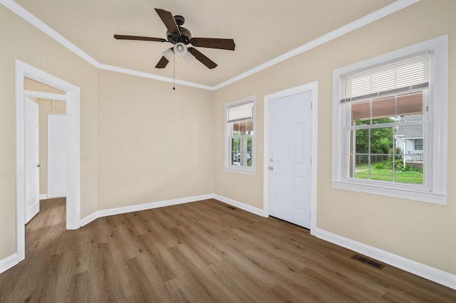 entrance foyer featuring wood finished floors, healthy amount of natural light, baseboards, and ornamental molding