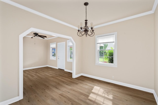 unfurnished dining area featuring wood finished floors, baseboards, a chandelier, crown molding, and arched walkways