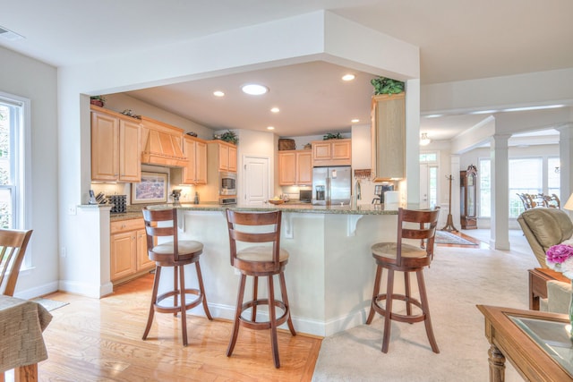 kitchen with appliances with stainless steel finishes, light brown cabinetry, a breakfast bar, and recessed lighting