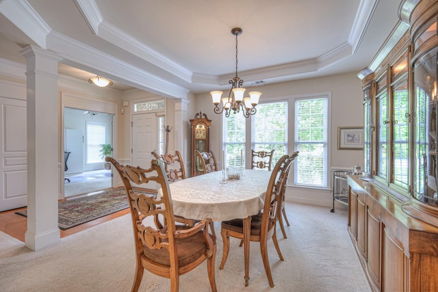 dining space with ornamental molding, light carpet, a tray ceiling, a chandelier, and decorative columns