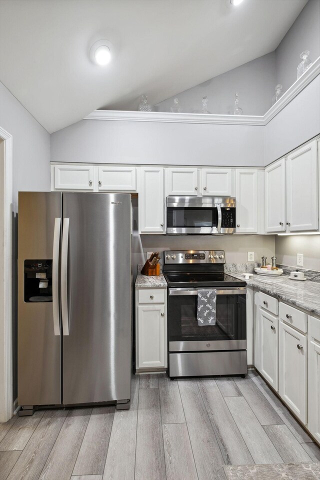 825 S Browns Ln Unit 1501, Gallatin, TN 37066 - kitchen featuring appliances with stainless steel finishes, vaulted ceiling, white cabinetry, light wood-style floors, and light stone counters