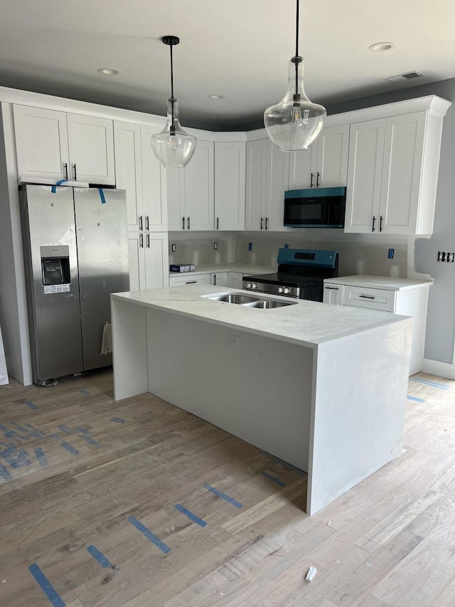507 Demoss St Unit 110, Gallatin, TN 37066 - kitchen featuring stainless steel appliances, light wood-type flooring, white cabinetry, decorative light fixtures, and light countertops