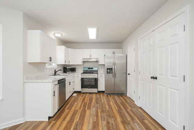 1011 Bon Meade Dr, Burns, TN 37029 - kitchen with stainless steel appliances, under cabinet range hood, a sink, wood finished floors, and white cabinets